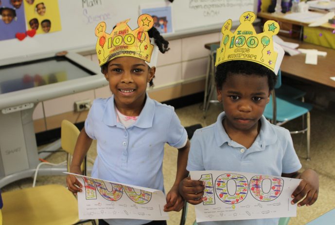 students with crowns and 100 paper